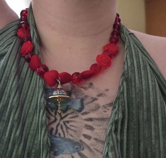 A necklace composed of red heart shaped gems. It has a blue UFO pendant. A necklace composed of red heart shaped gems. It has a blue UFO pendant.